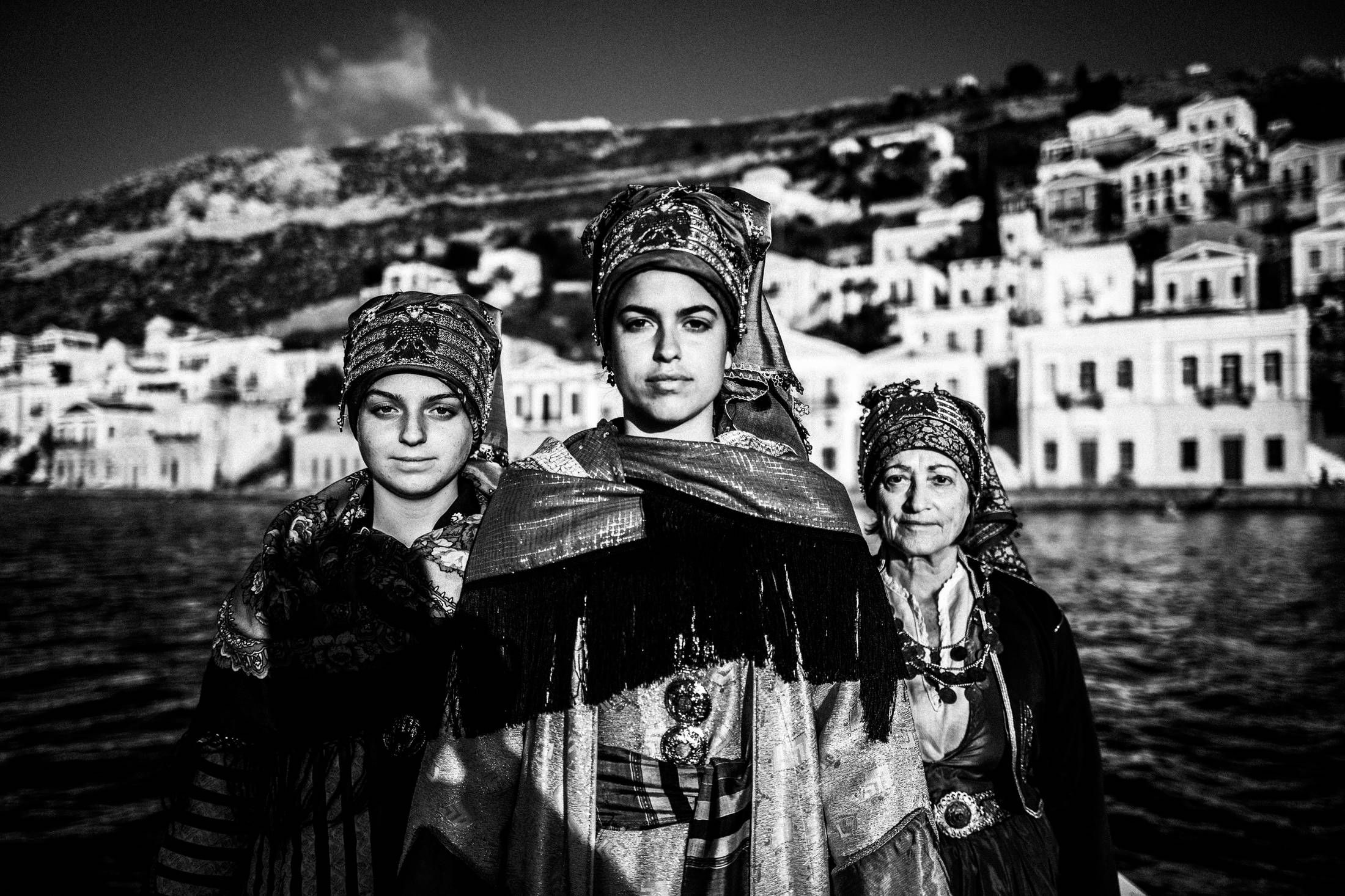 Traditional costumes at the harbour of Symi, by photographer George Tatakis