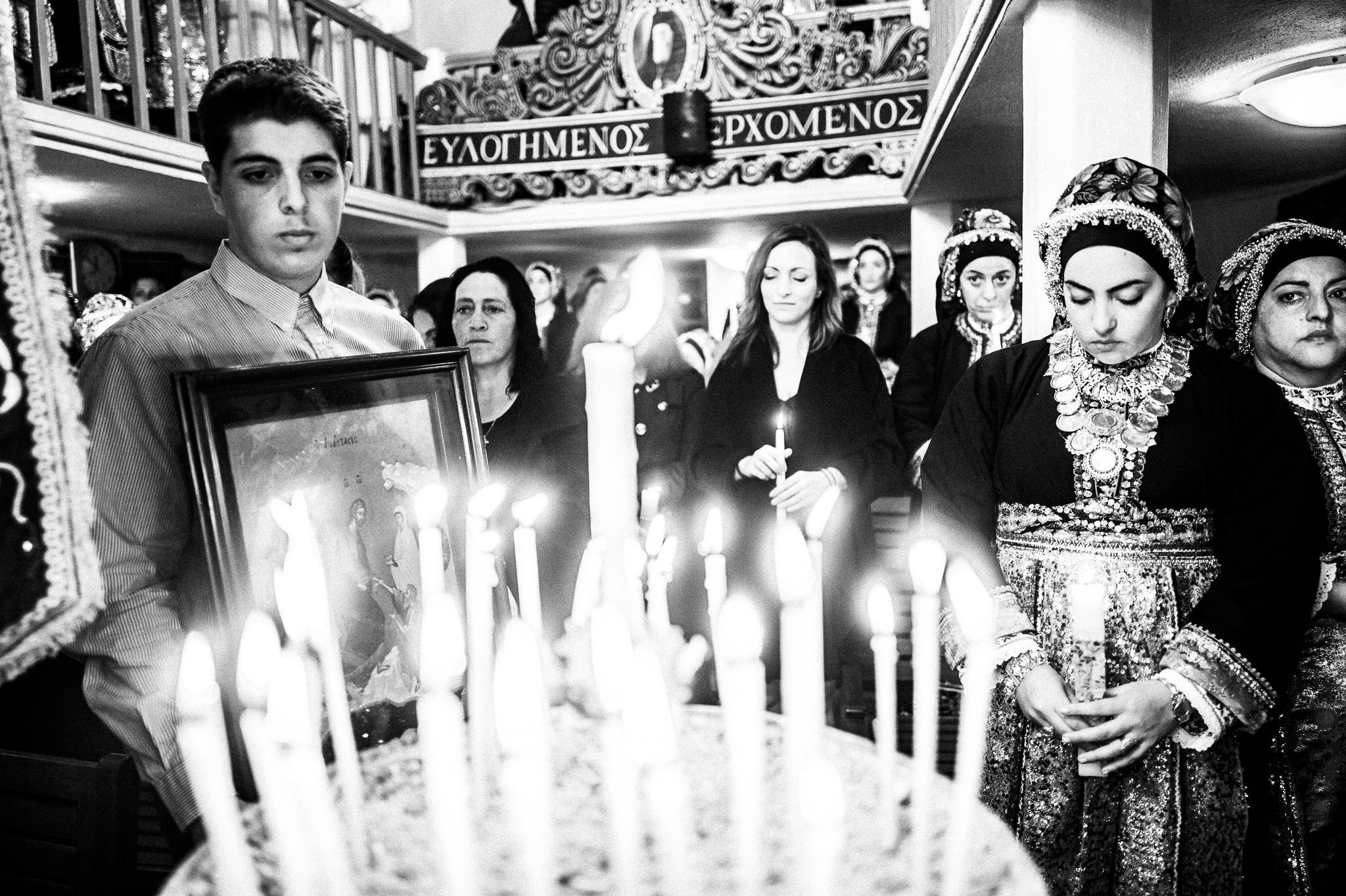 The proclamation of the Resurrection inside the local church. A group of women and a boy behind lit candles. Olympos, Karpathos, Greece. 