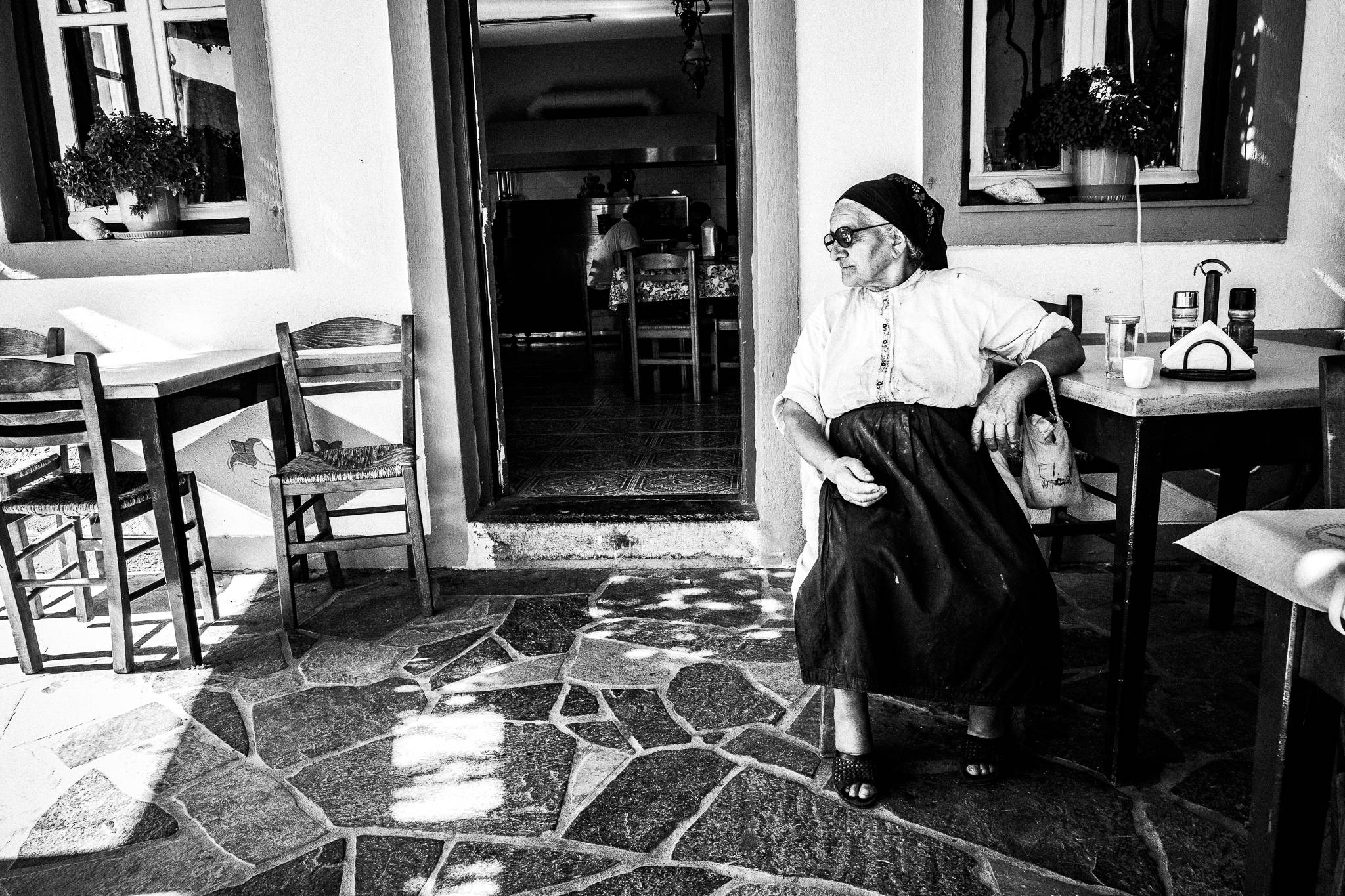 Irene at the local tavern in Avlona, Olympos, Karpathos, Greece. Black and white photography by George Tatakis