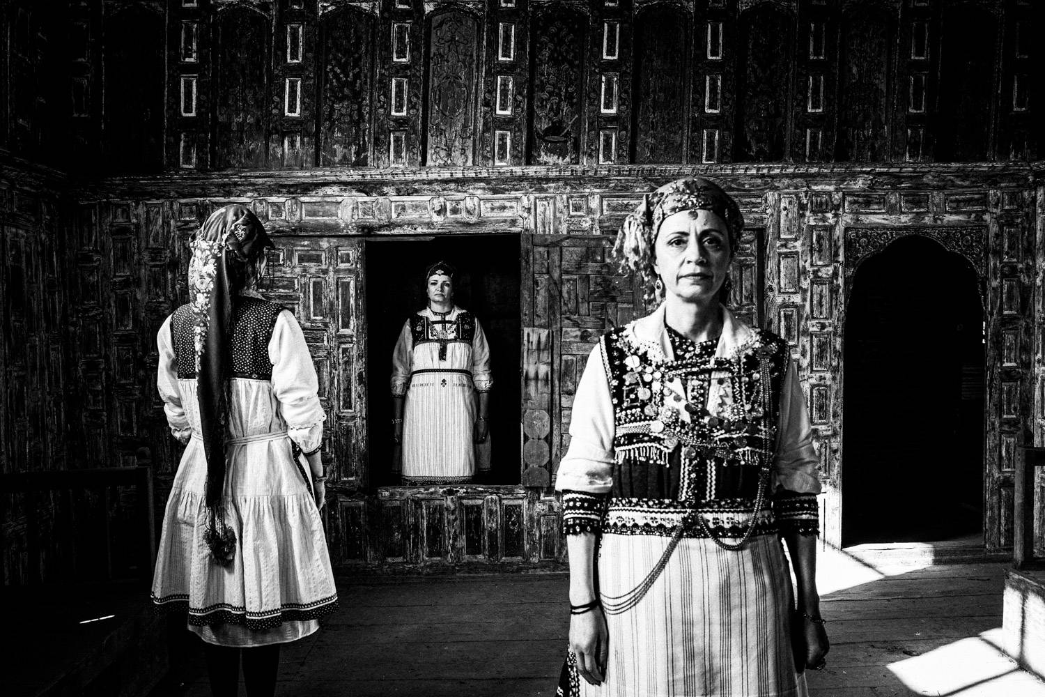 Three women inside a Mansion in Siatista, wearing the traditional costumes of Tsartsampas. Macedonia, Greece. Black and white photograph by George Tatakis