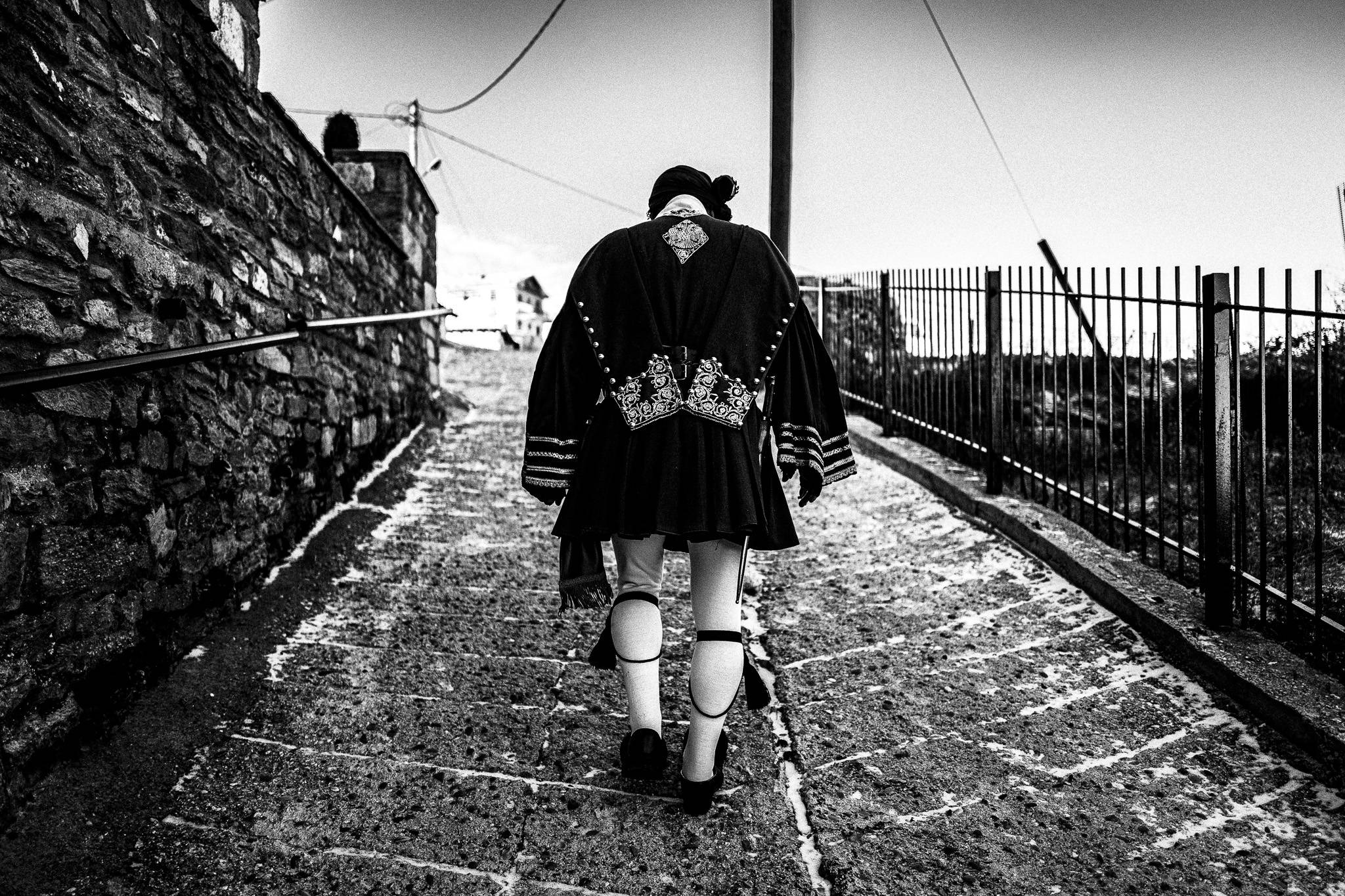 A man in the traditional costume walking round Klisoura, Pagan Christmas customs of Northern Greece, by photographer George Tatakis