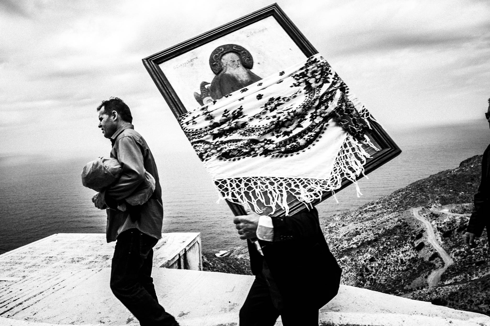 A man carrying a wooden Orthodox Icon, overlooking the Aegean. Olympos, Karpathos, Greece. 