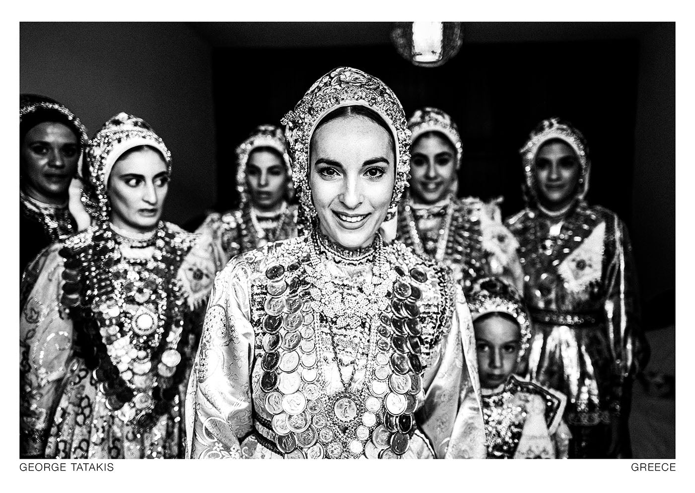 A bride with her friends, exiting her room during her wedding day in Diafani, Olympos, Karpathos, Dodecanese, Greece. Black and white photography postcard by George Tatakis, project Caryatis.