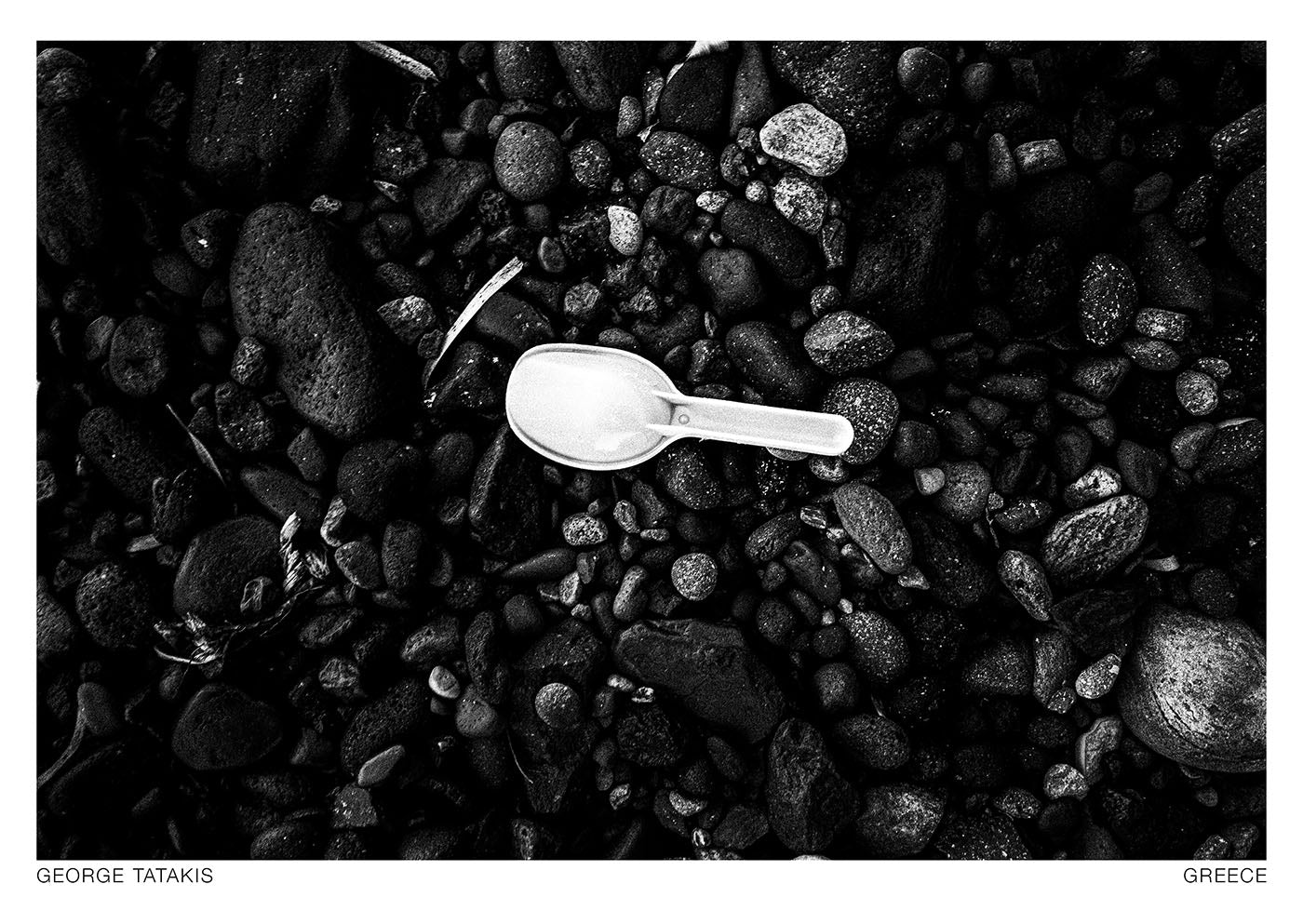 A toy shovel on black volcanic pebbles, from the new project Chorōs – a study of the intrinsic qualities of music and rhythm in static visual stimuli. Black and white photography postcard by George Tatakis, project Chorōs.