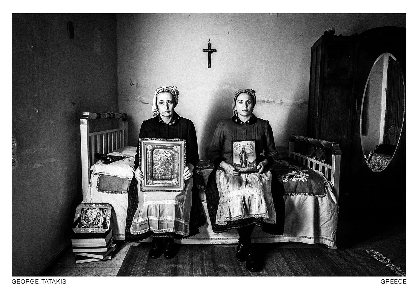 Two women posing inside an abandoned house at Divri, Lamia, Greece. They are holding greek-orthodox icons. Black and white photography postcard by George Tatakis, project Caryatis.